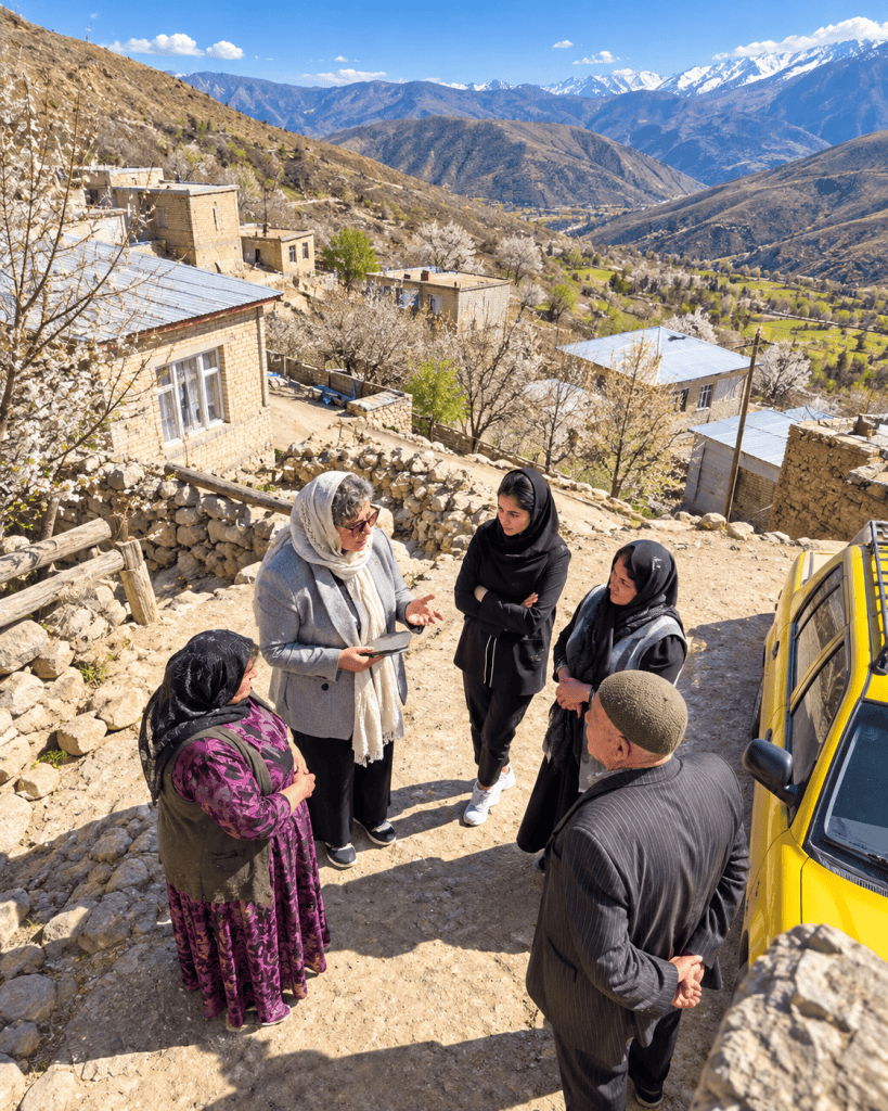 نمایی از بالا از گفت‌وگوی گروهی اعضای مؤسسه مهر شمس آفرید با یکی از اهالی روستا، در میان خانه‌های روستایی و طبیعت کوهستانی
